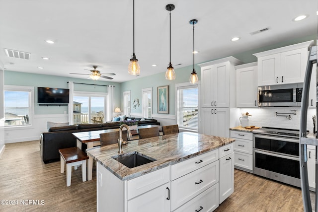 445 E Third St, Ocean Isle Beach, NC 28469 - kitchen featuring stainless steel appliances, a sink, a kitchen island with sink, light wood-type flooring, and recessed lighting