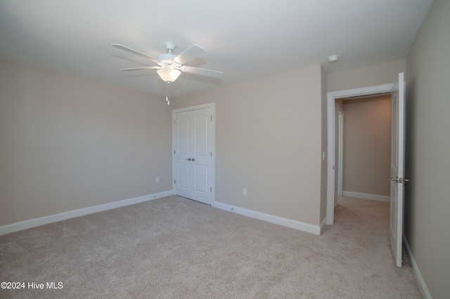 unfurnished bedroom with ceiling fan, a closet, and light carpet