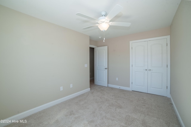 unfurnished bedroom featuring ceiling fan, a closet, and light colored carpet