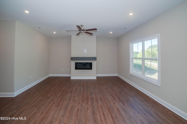 unfurnished living room featuring ceiling fan and dark wood-type flooring