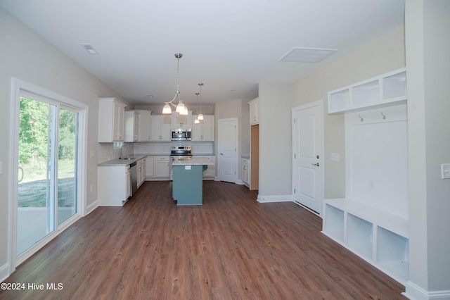 kitchen featuring dark hardwood / wood-style flooring, stainless steel appliances, a center island, white cabinetry, and hanging light fixtures