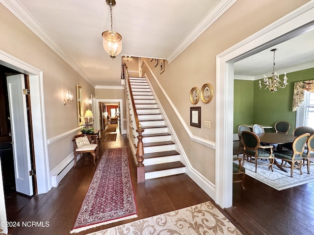 entrance foyer featuring a baseboard heating unit, ornamental molding, dark wood finished floors, and an inviting chandelier