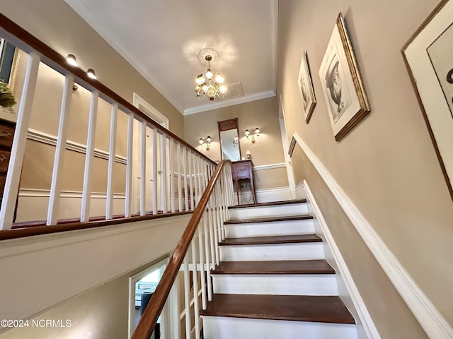 stairs with ornamental molding and a notable chandelier