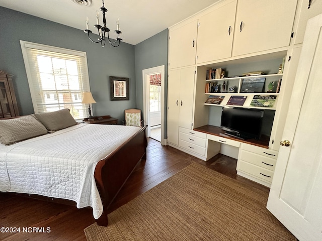 bedroom with a chandelier, dark wood-type flooring, built in study area, and visible vents