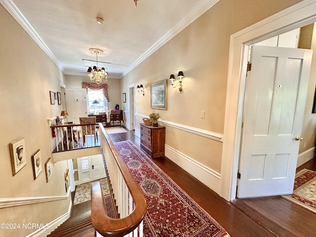 hall with baseboards, a notable chandelier, ornamental molding, and dark wood-style flooring