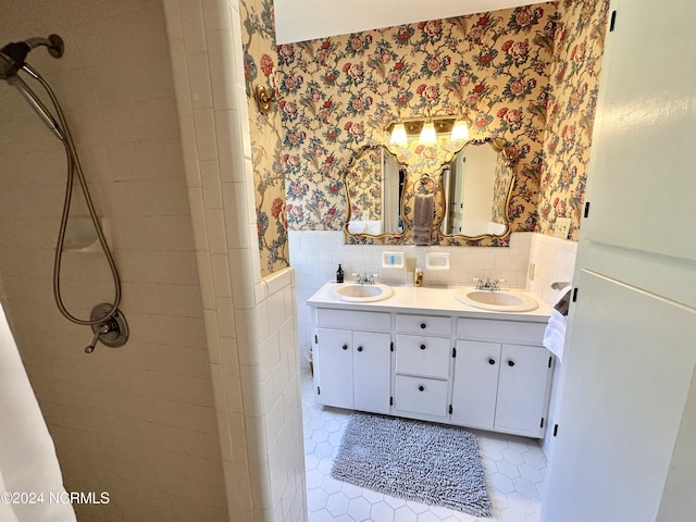 full bathroom with a wainscoted wall, a sink, and wallpapered walls