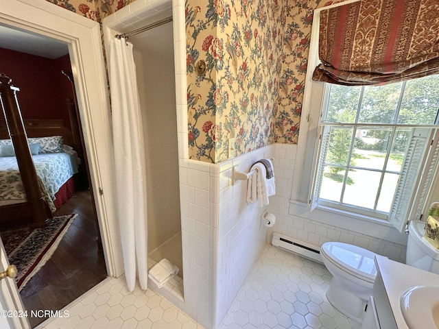 full bath with connected bathroom, a baseboard heating unit, a wainscoted wall, a shower stall, and wallpapered walls