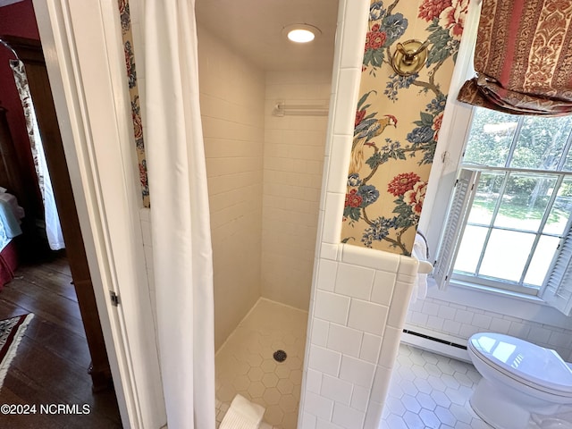 full bath featuring a wainscoted wall, tile walls, baseboard heating, a shower stall, and wallpapered walls