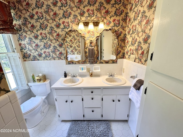 full bathroom featuring wainscoting, a sink, and wallpapered walls