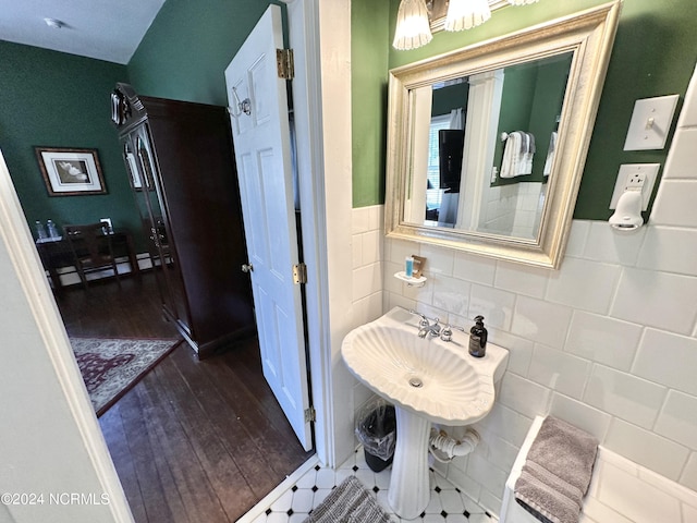 half bathroom featuring a wainscoted wall, wood finished floors, and tile walls