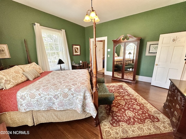 bedroom with lofted ceiling, an inviting chandelier, baseboards, and dark wood-type flooring