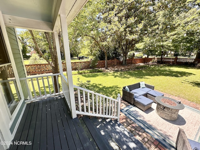 wooden deck with an outdoor fire pit, a fenced backyard, and a yard