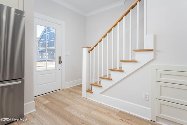 foyer with ornamental molding and light wood-type flooring