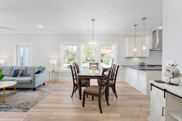 dining space featuring light wood-type flooring and ornamental molding