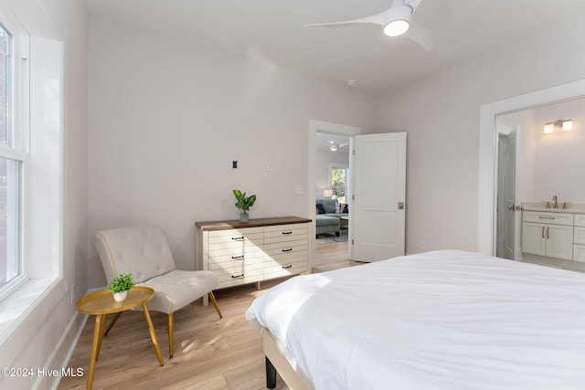 bedroom featuring light wood-type flooring, ensuite bathroom, and ceiling fan