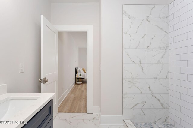 bathroom with vanity, wood-type flooring, and tiled shower