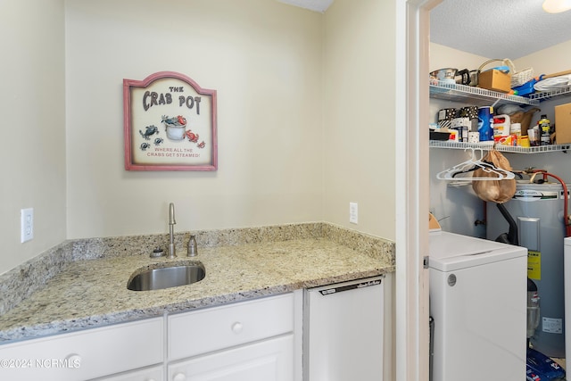 clothes washing area with a textured ceiling, sink, washer / dryer, and electric water heater