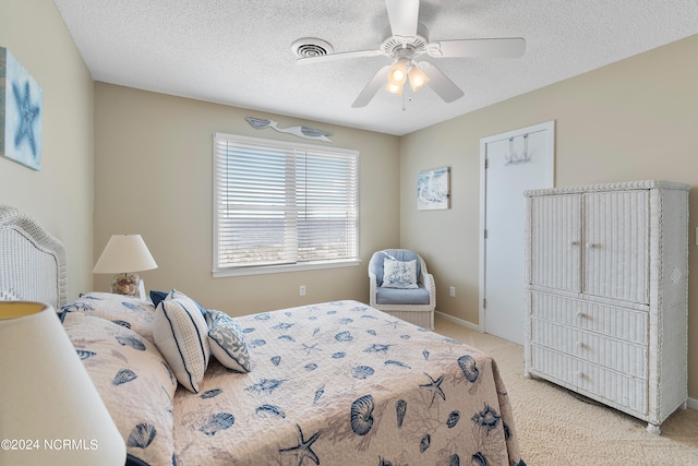 bedroom featuring light carpet, ceiling fan, and a textured ceiling