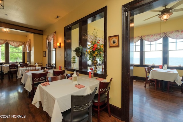 dining room with plenty of natural light, ceiling fan, a water view, and wood-type flooring