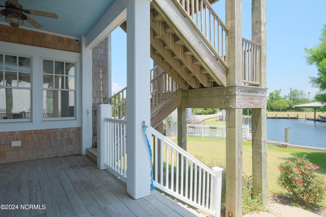 deck with ceiling fan, a water view, and a yard