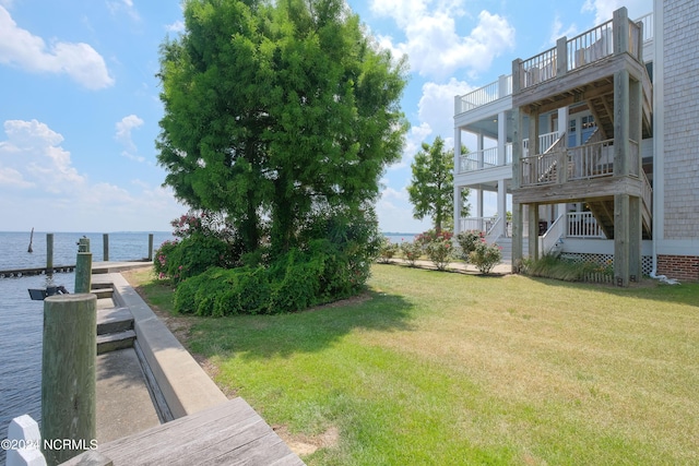 view of yard featuring a balcony, a water view, and a boat dock