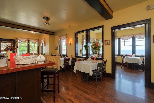 dining area with beamed ceiling, dark hardwood / wood-style flooring, and a water view