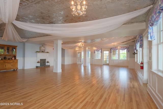 108 Wharf Landing Dr, Edenton, NC 27932 - unfurnished living room featuring a chandelier, a fireplace with raised hearth, an ornate ceiling, wood finished floors, and a decorative wall