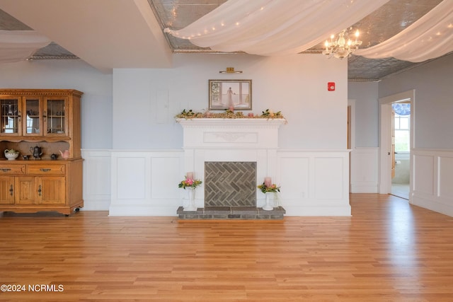 108 Wharf Landing Dr, Edenton, NC 27932 - unfurnished living room featuring a chandelier, light wood-type flooring, a decorative wall, wainscoting, and a fireplace