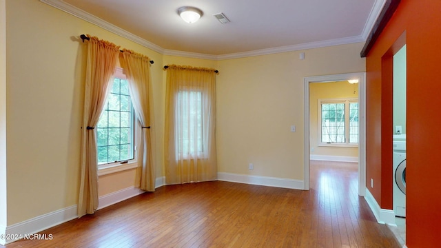 spare room featuring light wood-type flooring, ornamental molding, and a wealth of natural light