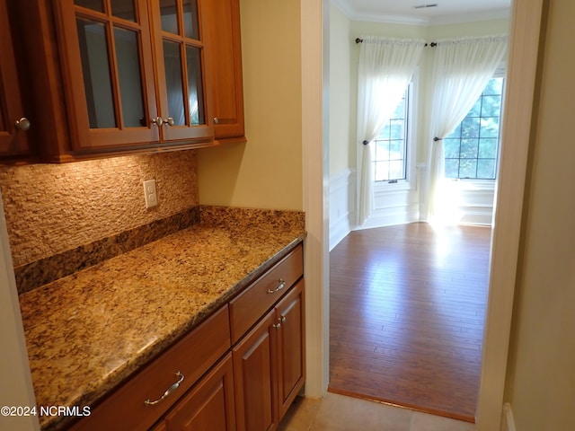 interior space featuring decorative backsplash, crown molding, light stone counters, and light wood-type flooring