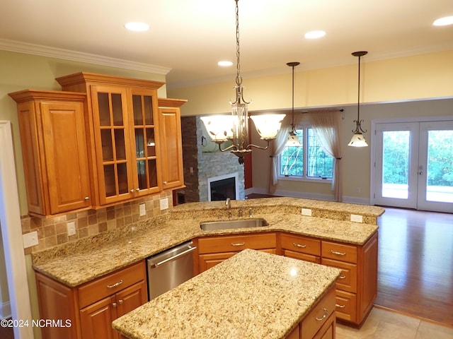 kitchen with dishwasher, sink, a stone fireplace, crown molding, and decorative light fixtures