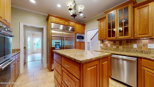 kitchen with a notable chandelier, built in appliances, ornamental molding, tasteful backsplash, and decorative light fixtures