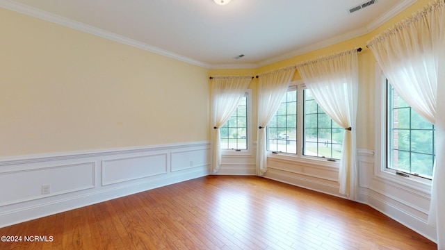 unfurnished room featuring light hardwood / wood-style floors, a wealth of natural light, and ornamental molding