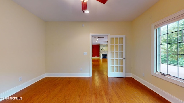 empty room with ceiling fan, light wood-type flooring, and french doors