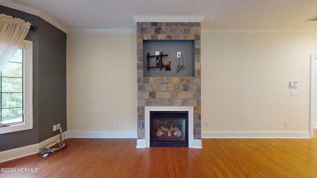 unfurnished living room with hardwood / wood-style flooring, a large fireplace, and ornamental molding