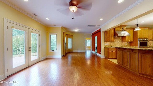 kitchen with french doors, extractor fan, decorative light fixtures, light hardwood / wood-style floors, and oven