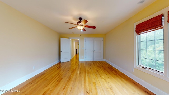 unfurnished bedroom featuring ceiling fan, a closet, and light wood-type flooring