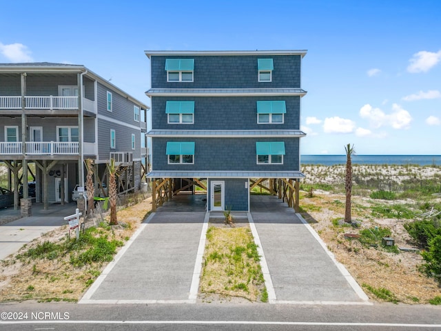 beach home featuring a carport, a water view, and driveway