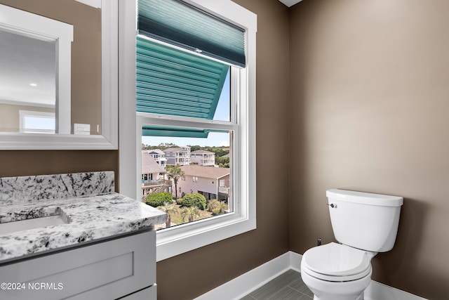 bathroom with toilet, baseboards, a wealth of natural light, and vanity