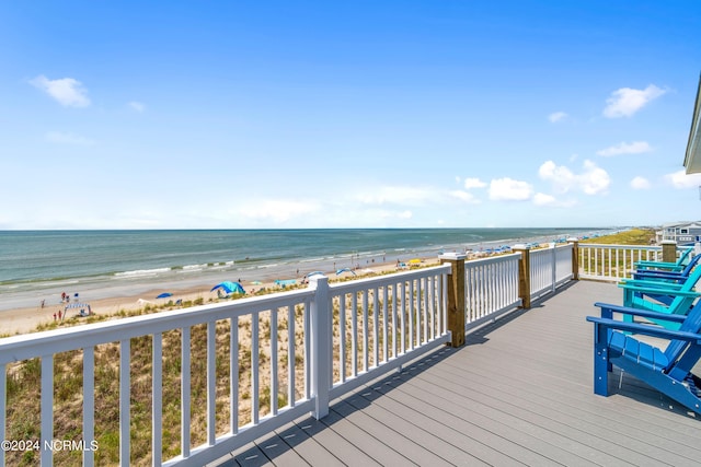 wooden deck with a water view and a beach view