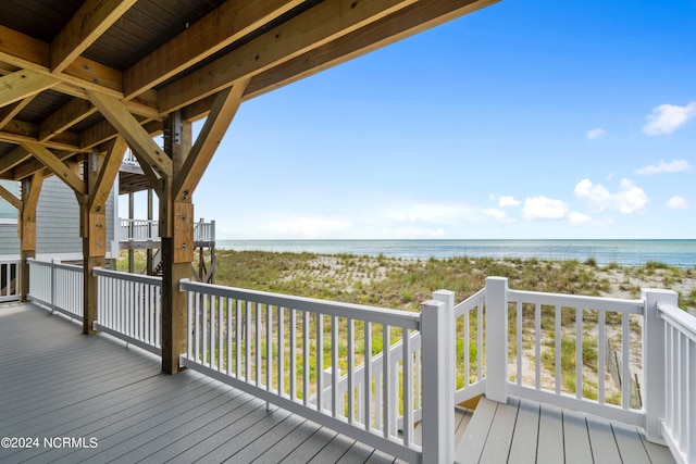 wooden deck featuring a water view and a beach view