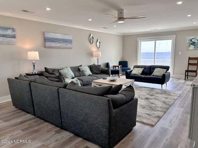 living area with baseboards, light wood-style floors, a water view, and crown molding