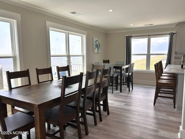 dining room featuring visible vents, crown molding, and light wood-style flooring