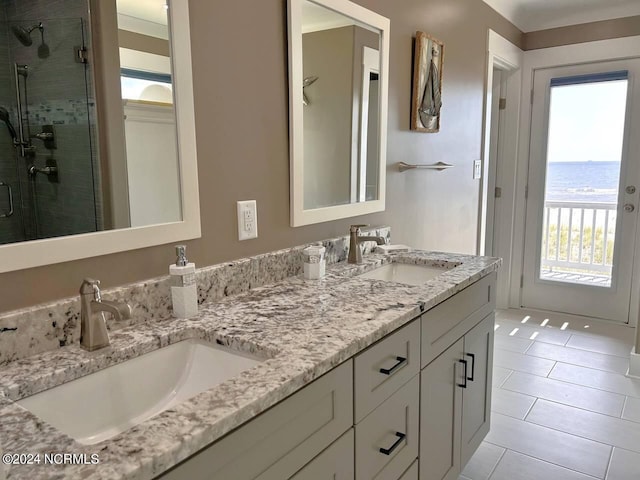 full bathroom featuring a water view, a stall shower, double vanity, and a sink