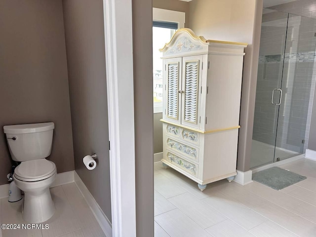 bathroom featuring tile patterned flooring, baseboards, a shower stall, and toilet