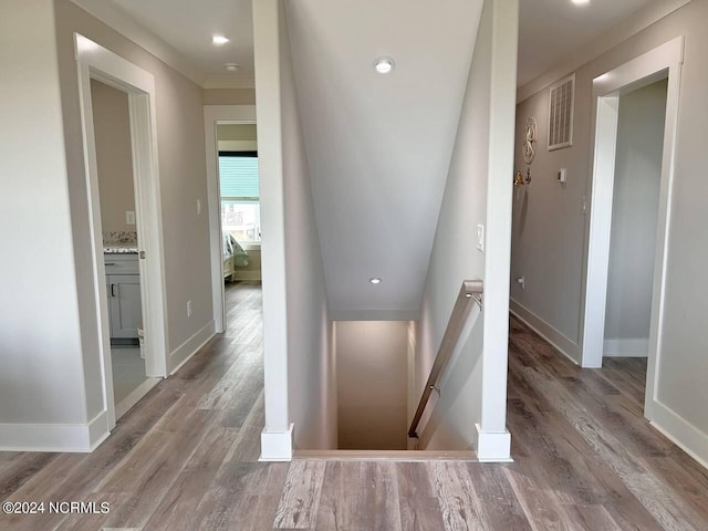 corridor featuring recessed lighting, baseboards, wood finished floors, and an upstairs landing