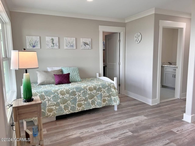 bedroom with light wood-style floors, ornamental molding, and baseboards