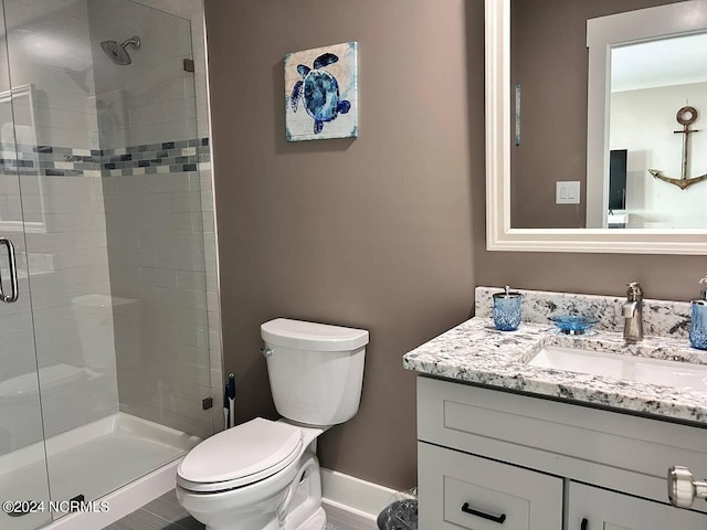 bathroom with a stall shower, vanity, toilet, and baseboards