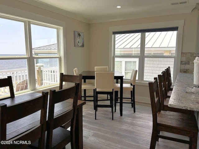 dining space featuring a water view, wood finished floors, visible vents, and baseboards