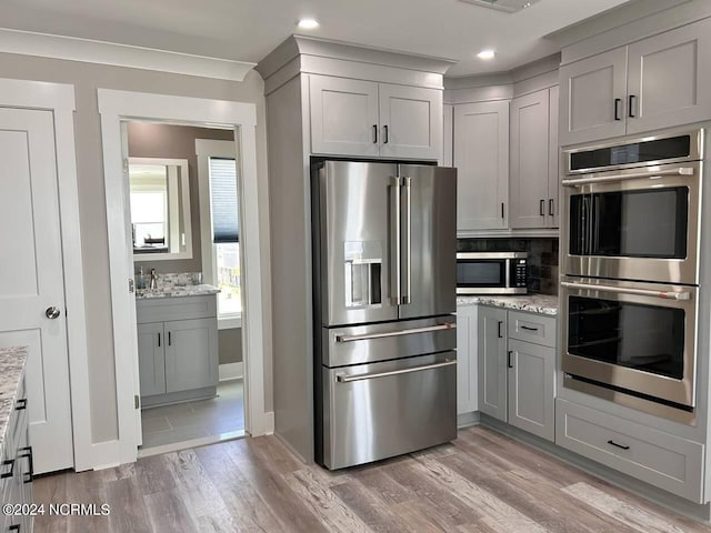 kitchen with light stone countertops, appliances with stainless steel finishes, and gray cabinets